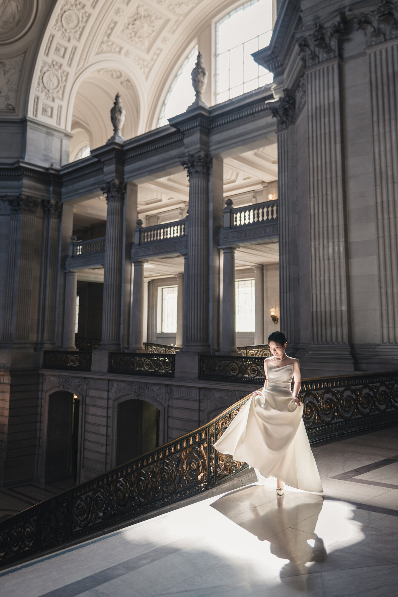 Bride moving through sunlight inside San Francisco City Hall