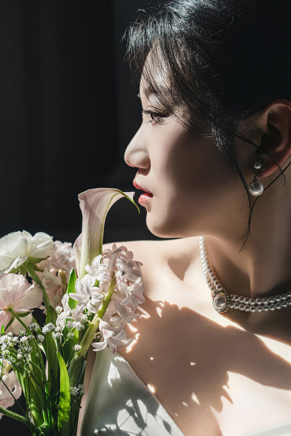 Close bridal profile with bouquet and window light
