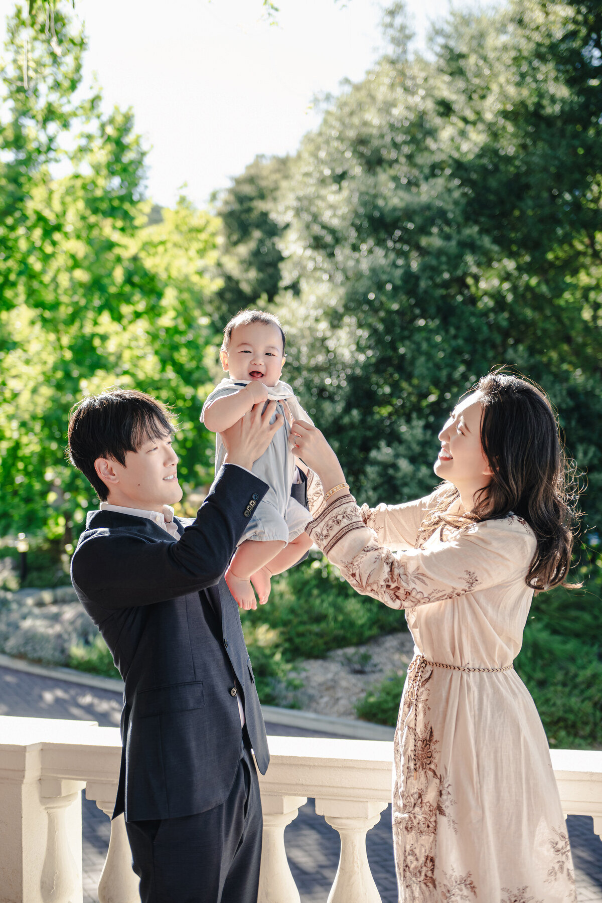 Vertical family portrait with parents lifting their baby