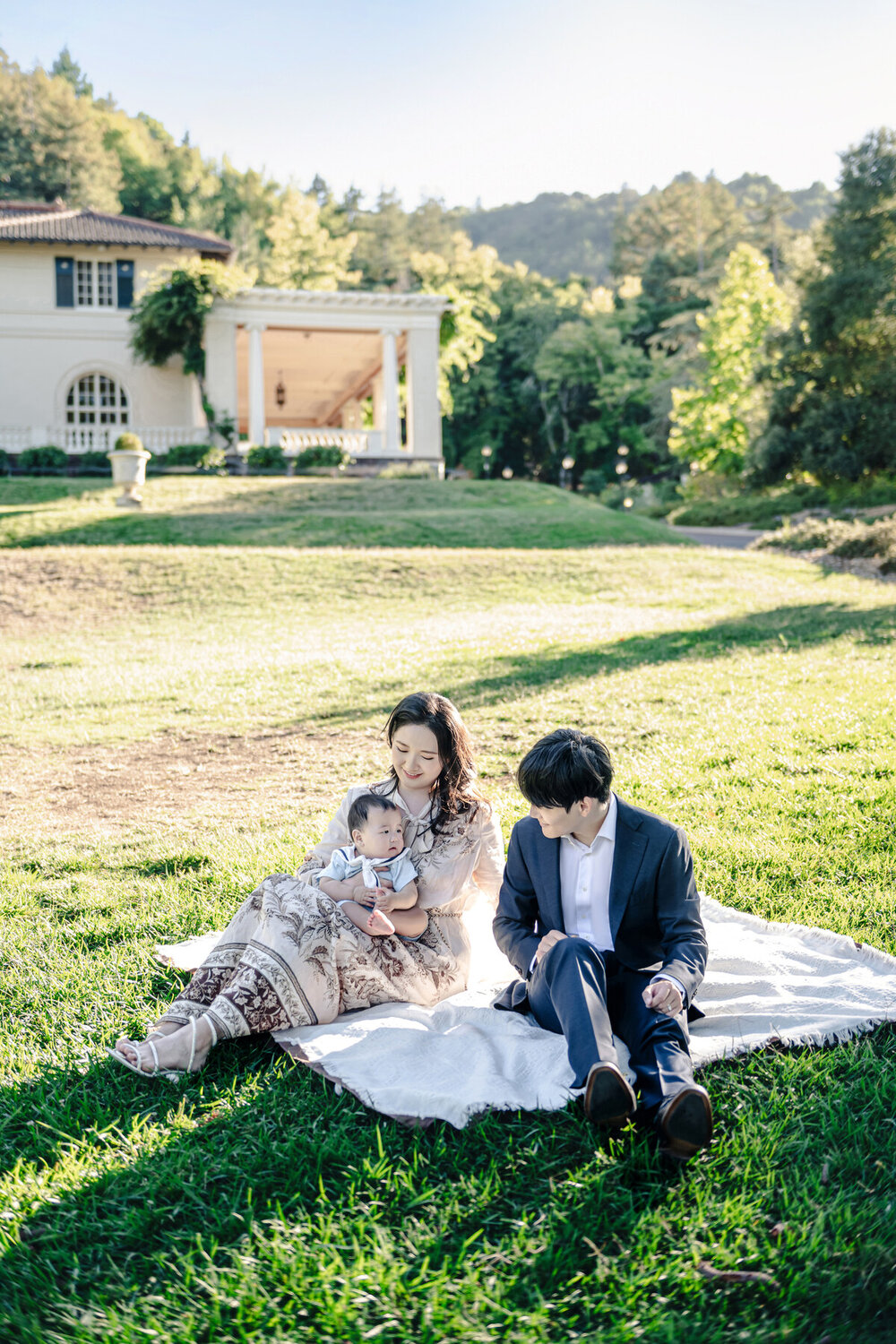 Family portrait of parents with baby on an estate lawn