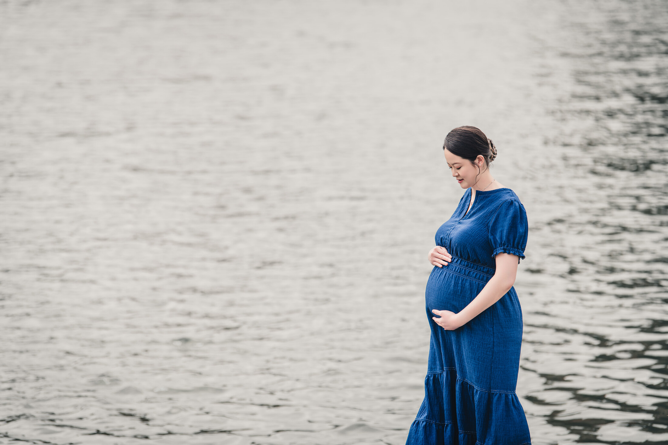 Outdoor maternity portrait by the water with quiet negative space