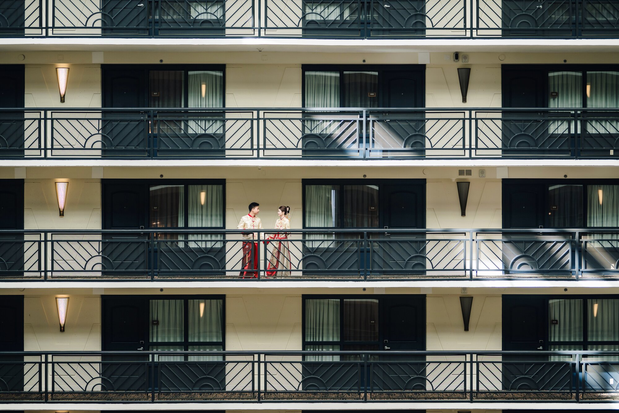 Couple in traditional Chinese wedding attire on a hotel balcony