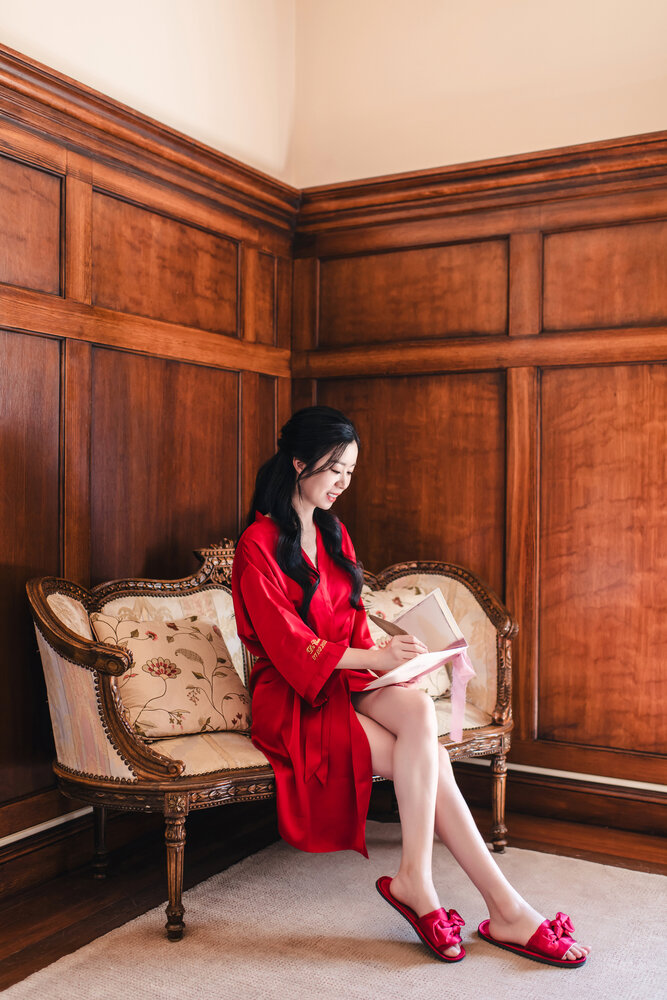 Bride in a red robe seated in the room