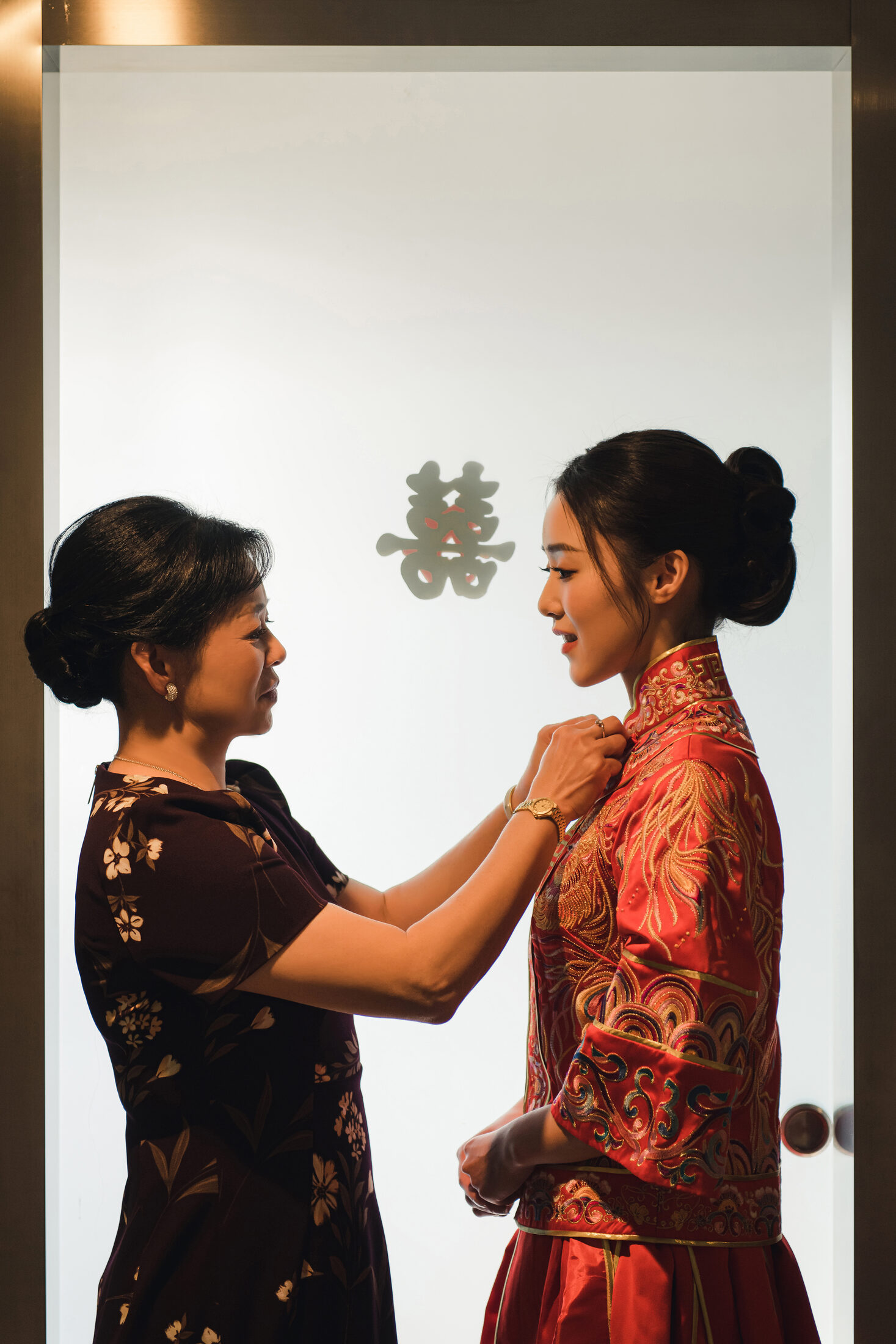 Mother adjusting the bride's red dress