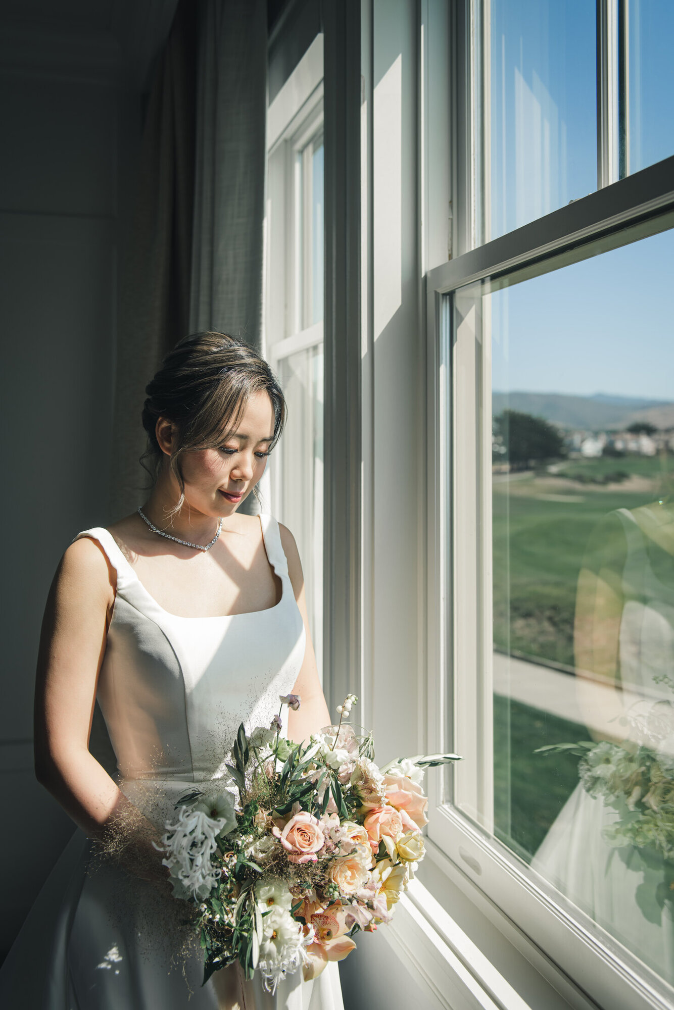 Bride with bouquet by the window