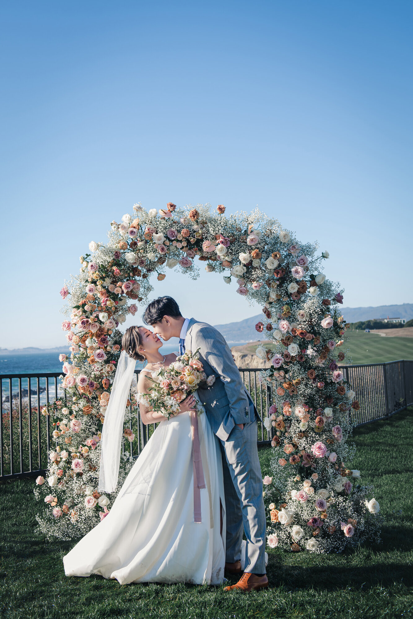 Couple kissing beneath the floral arch