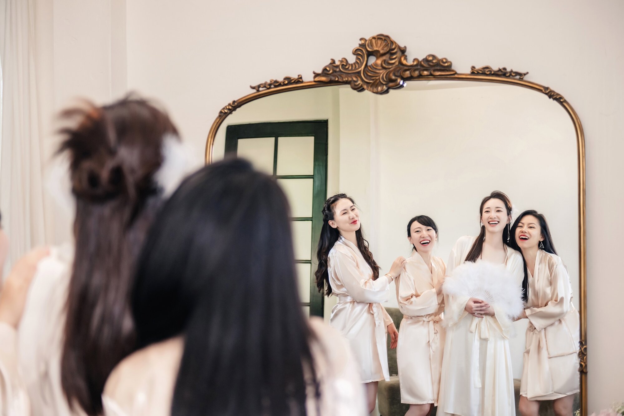 Bride and bridesmaids by the mirror
