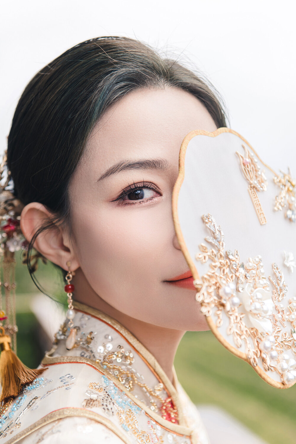 Bride holding a fan in red Chinese wedding attire
