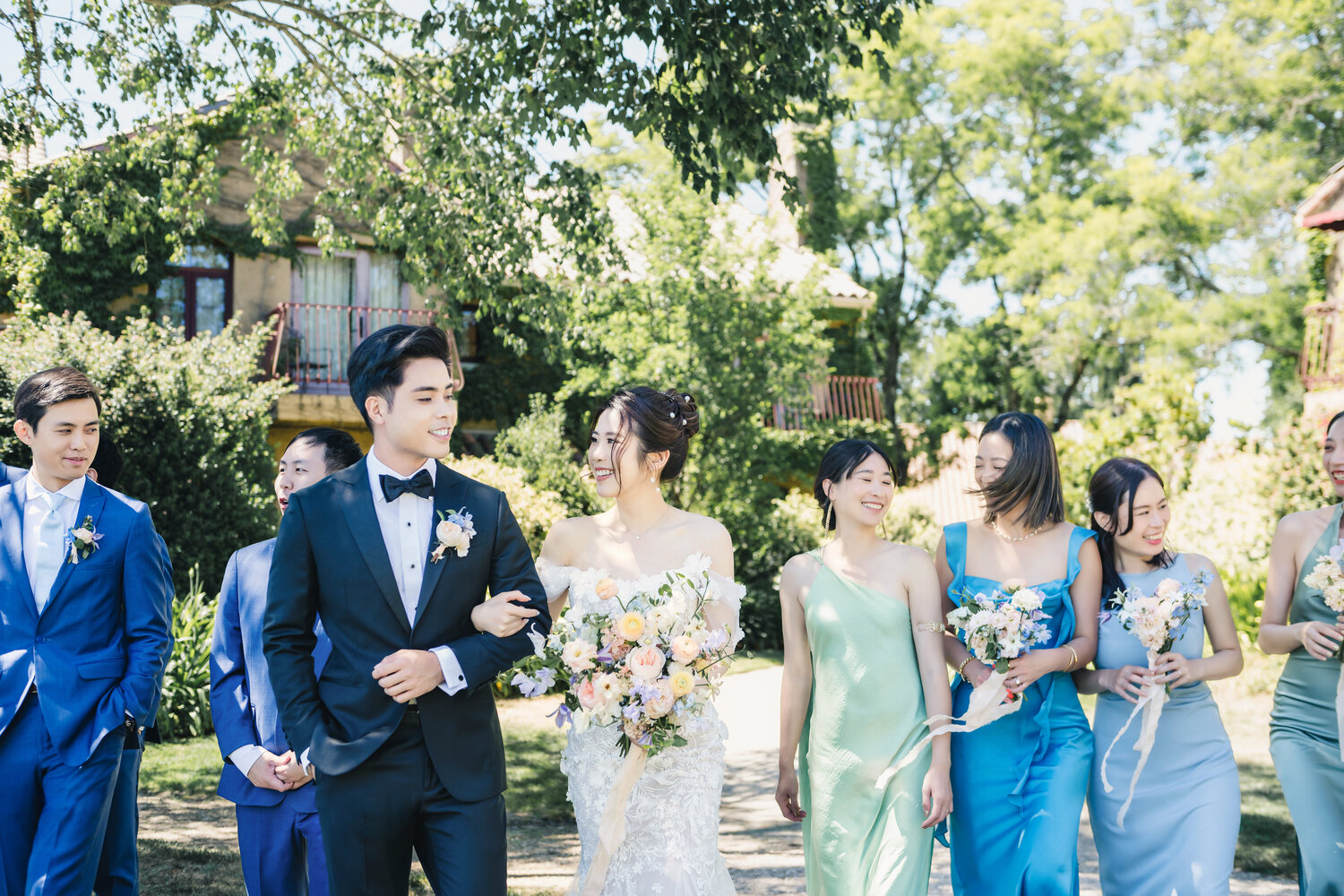 Groom walking with bridesmaids through the garden