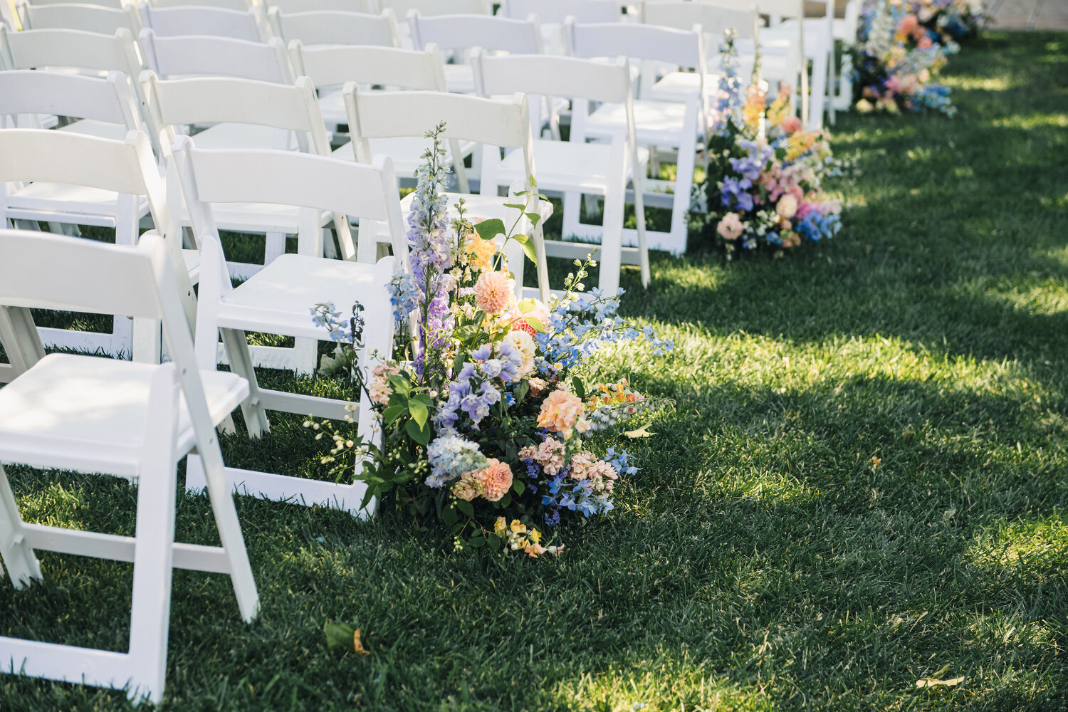 Ceremony aisle flowers and white chairs
