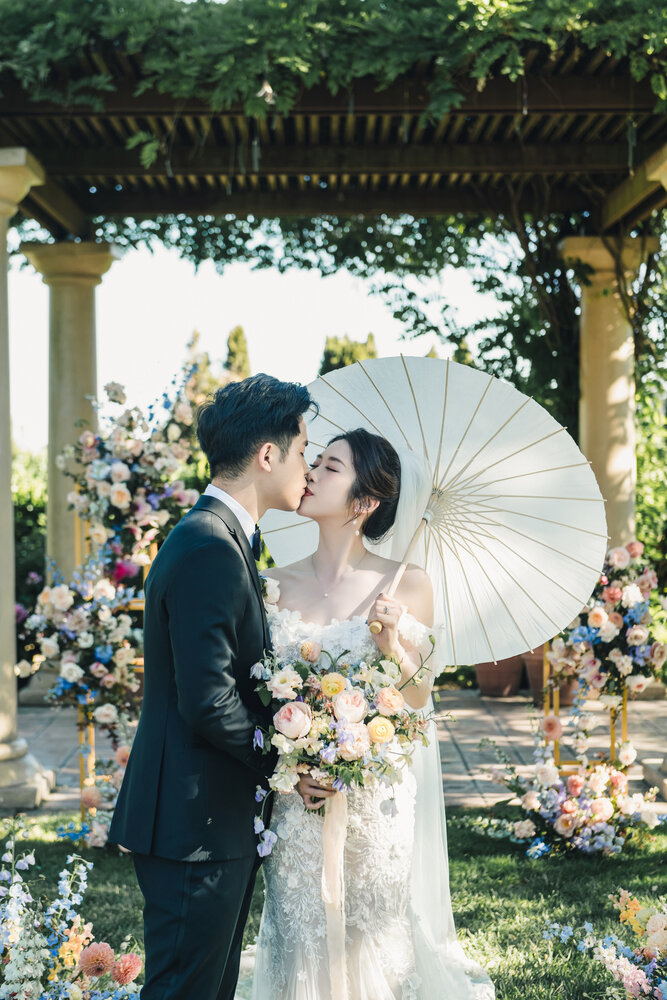 Couple kissing beneath parasols