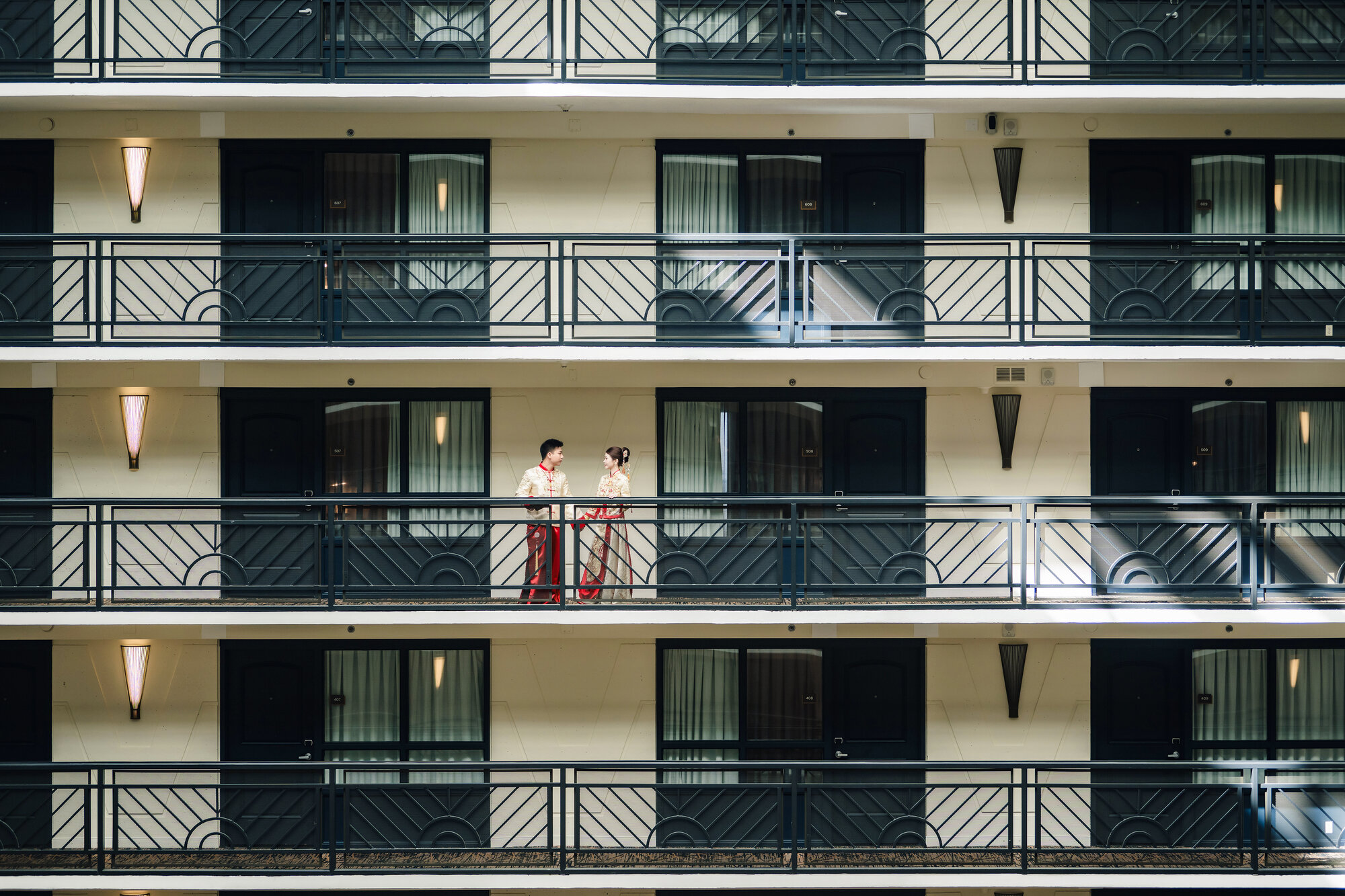 Couple in traditional Chinese wedding attire on a hotel balcony